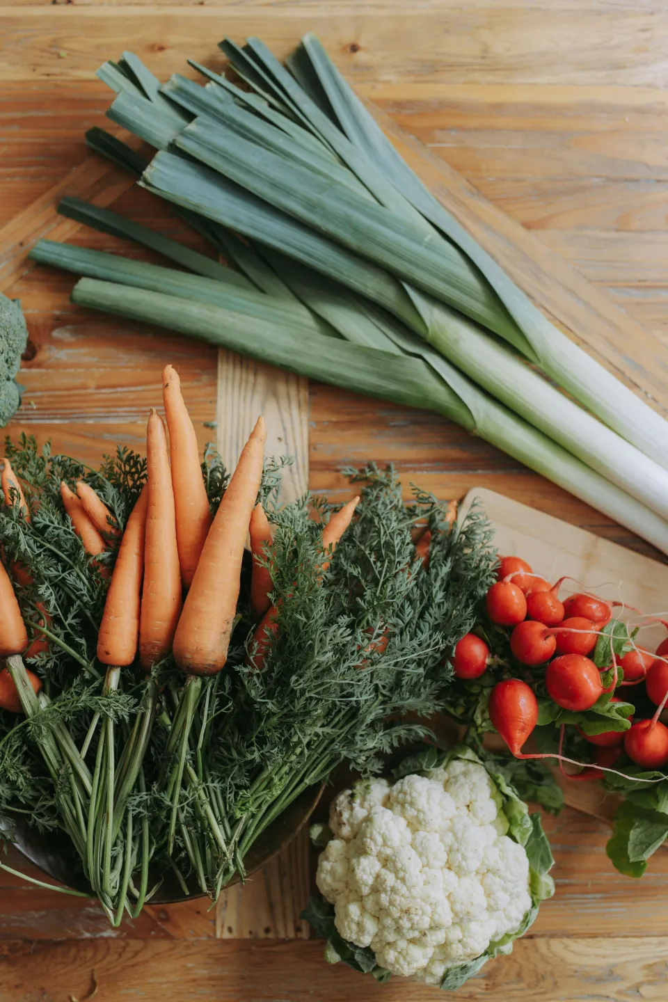 Poireaux, carottes et chou-fleur du maraîcher sur une table en bois