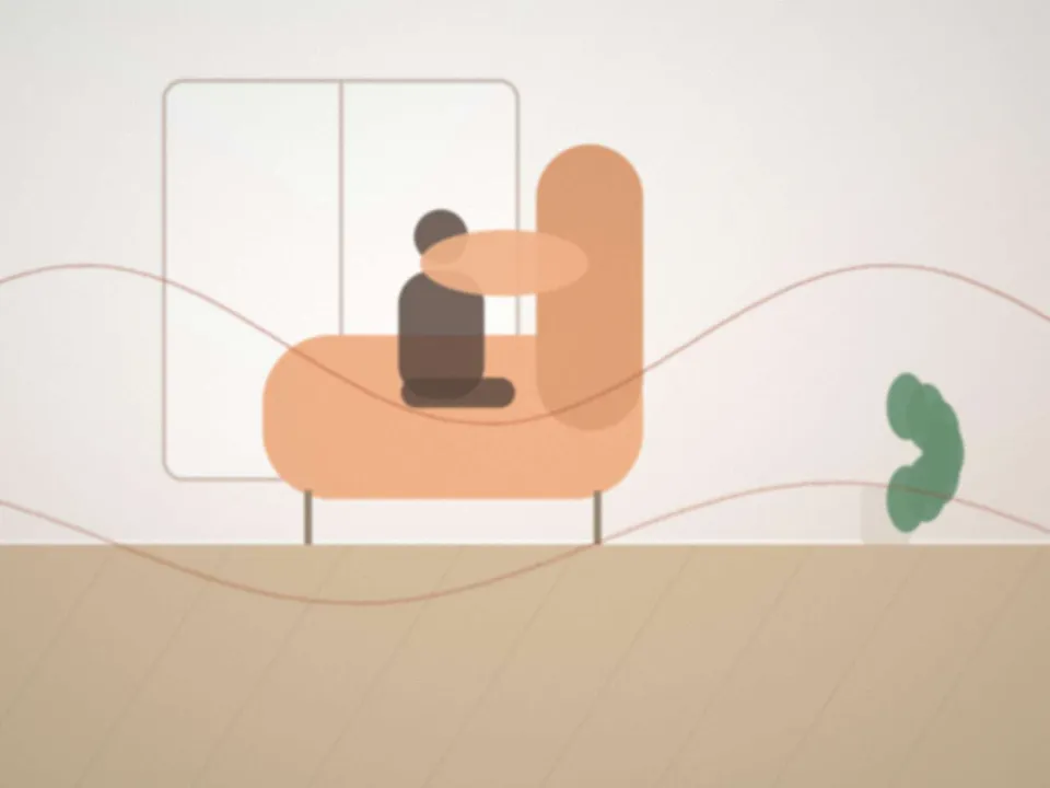 Une mère de dos, assise dans un fauteuil avec un coussin d'allaitement