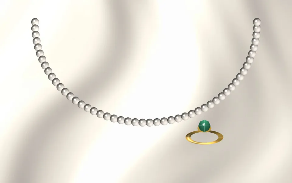 Rang de perles et bague émeraude sur un drapé ivoire