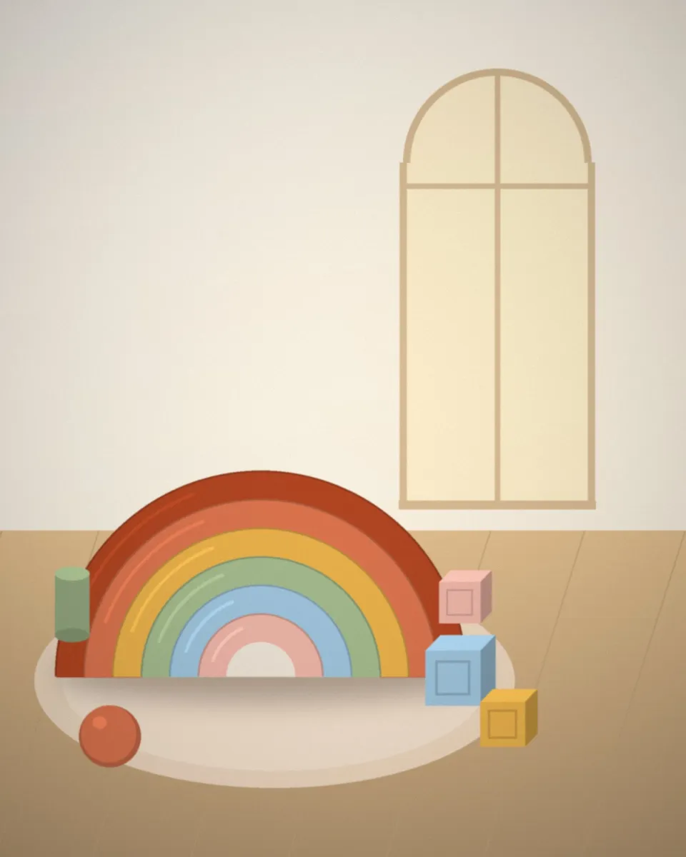 Un arc-en-ciel en bois et des cubes colorés posés sur un tapis, dans la salle de jeux baignée de lumière