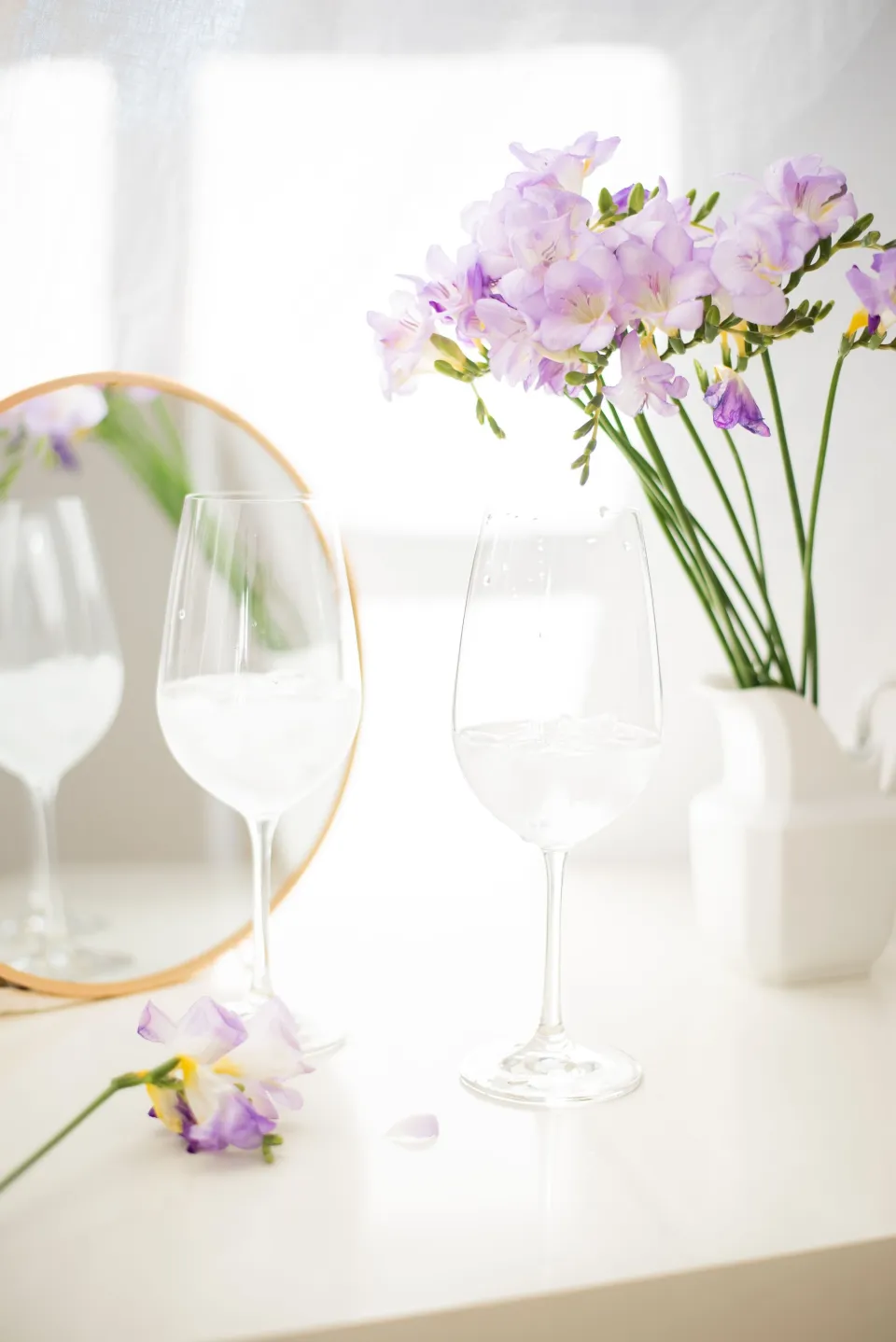 Table dressée près de la fenêtre, verres et fleurs