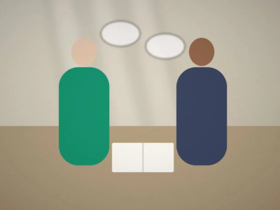 Deux adultes qui échangent en anglais, carnet de vocabulaire ouvert sur la table